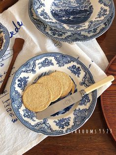 two blue and white plates with crackers on them sitting on a table next to utensils