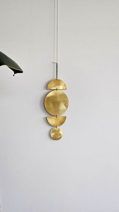 a clock hanging on the side of a white wall next to a potted plant