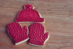 three decorated cookies with mittens and gloves on top of a wooden table next to each other