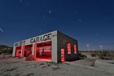 an old gas station with red lights on it's side and stars in the sky