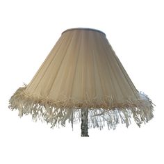 a lamp that is on a table with a light shade over it and fringes