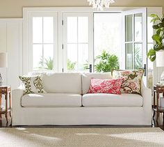 a living room filled with furniture and lots of window sill space next to a white couch