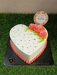 a heart shaped cake sitting on top of a black plate covered in frosting and flowers