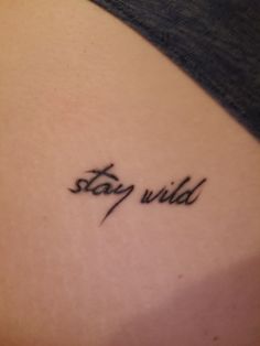 a tattoo saying stay wild on the back of a woman's left arm,