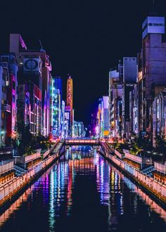 the city is lit up at night and reflecting in the water with lights on it