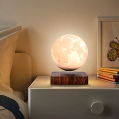 the moon lamp is sitting on top of a night stand