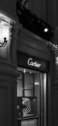 a black and white photo of a cartier storefront at night with lights on