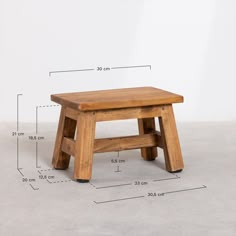 a small wooden stool sitting on top of a cement floor next to a measuring line