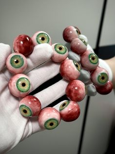 a hand is holding several bracelets made out of fake eyeballs and plastic gloves