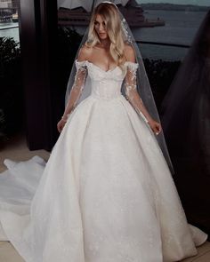 a woman in a wedding dress standing next to a window