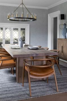 a dining room table with chairs and pictures on the wall above it, along with an area rug