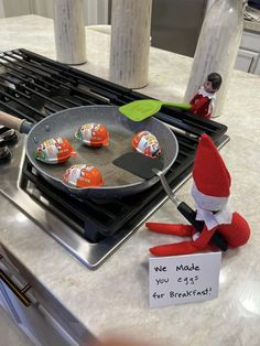 an elf frying marshmallows in a pan on the stove with a sign reading we made you eat for breakfast