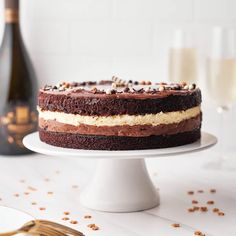 a chocolate cake sitting on top of a white plate next to a bottle of champagne