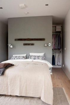 a bed sitting in a bedroom next to a wall mounted coat rack with clothes on it