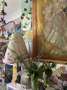 a vase filled with flowers sitting on top of a table next to a framed painting