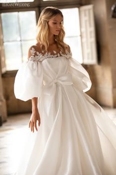 a woman in a white wedding dress with an off the shoulder bow