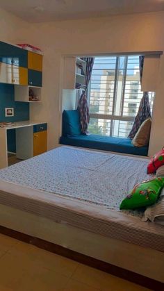 a bed room with a neatly made bed next to a window and a tv mounted on the wall