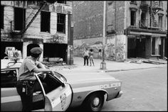 a police car parked in front of an old building with graffiti on the walls and people standing around it