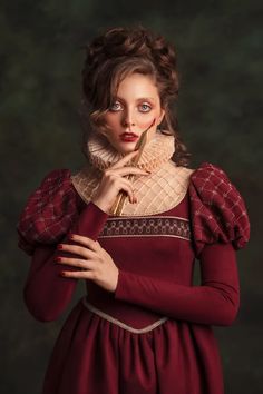 a woman in a red dress is posing with her hands on her face and looking at the camera