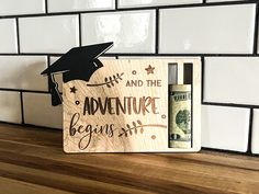 a wooden sign that says and the adventure begins with a bottle of wine in front of it