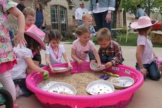 children are playing in a sandbox with their hands on the bowls and spoons