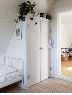 an attic bedroom with white painted walls and wooden floors