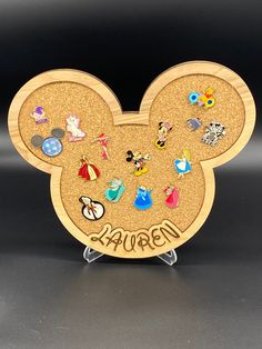 a wooden mickey mouse head with lots of disney pins on it's ears and name