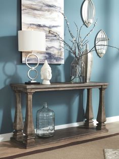 a table with vases and other items on it in front of a blue wall