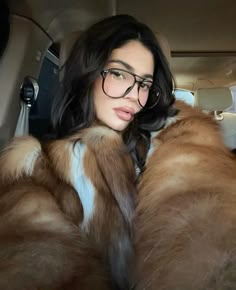 a woman wearing glasses sitting in the back seat of a car with fur on it