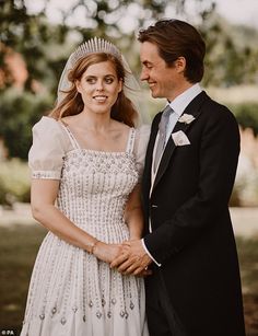 a man in a suit and tie standing next to a woman in a wedding dress