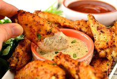 a person dipping sauce on some chicken wings