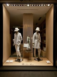 two mannequins dressed in white clothing and hats are standing in a store window