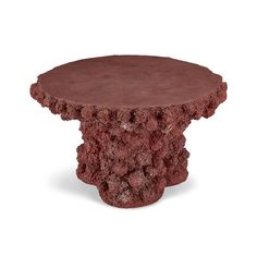 a small round table made out of red clay with an intricate design on the top