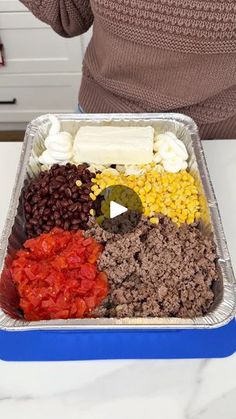 a person standing in front of a tray of food on top of a white counter