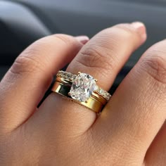 a woman's hand with two gold rings and a diamond ring on her finger