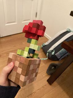 a person holding a wooden block in front of a door with a plant on it