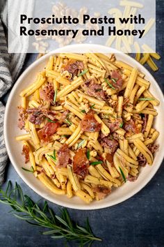 pasta with bacon and honey in a white bowl on a blue tablecloth next to a sprig of rosemary