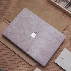 an apple laptop sitting on top of a table next to some other items and papers