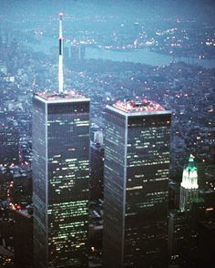 an aerial view of two skyscrapers in new york city at night with the lights on