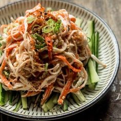 a white plate topped with noodles and veggies on top of a wooden table