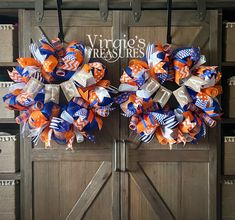 two wreaths with orange, white and blue bows are on display in front of a wooden door