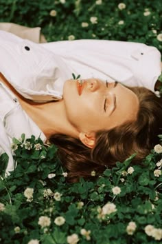 a woman laying in the grass with her eyes closed