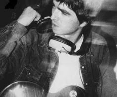 black and white photograph of a man with headphones on holding a guitar in his right hand