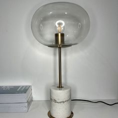 a table lamp sitting on top of a white counter next to a stack of books