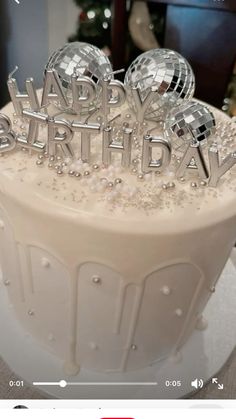 a birthday cake that is sitting on top of a table, with the words happy birthday written in silver letters