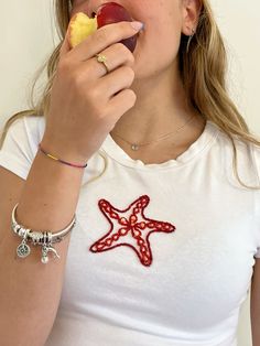 a woman eating an apple while wearing a starfish shirt