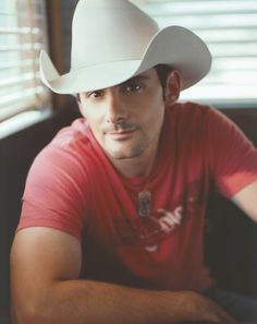 a man in a red shirt wearing a white cowboy hat and looking at the camera