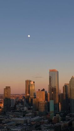 the moon is setting in the sky over a cityscape with tall buildings and skyscrapers