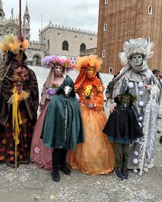 three people in costumes standing next to each other near a building with a clock tower