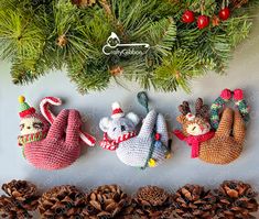 three knitted christmas ornaments sitting next to pine cones